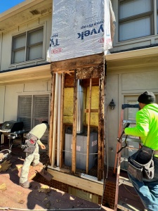 Contractors replacing wood rotted chimney supports on the outside of a house